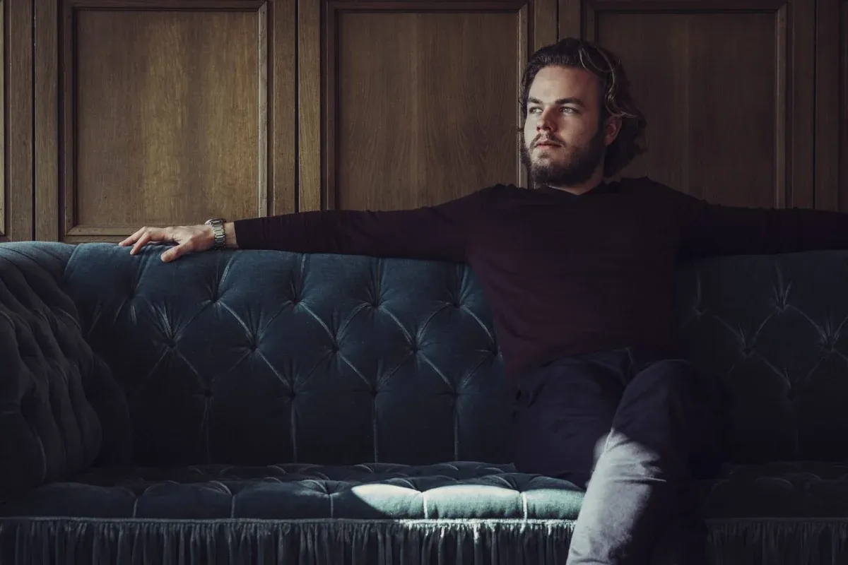 Nicolas Matt auf einem Sofa in einem holzgetäfelten Raum